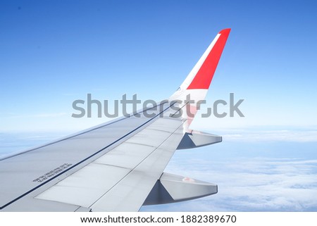 the beautiful white scenery on the plane looks forward to seeing a wing of plane, clouds,blue sky and mist.