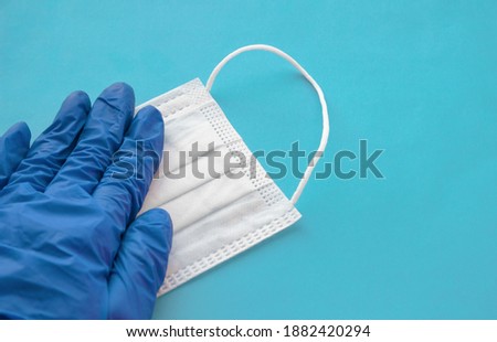 White medical mask and blue medical glove on blue background