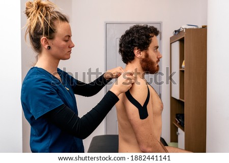 Stock photo of physiotherapist giving back massage to patient sitting in stretcher.
