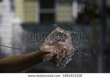 Water balloon bursting. High-speed photograph of a water-filled balloon being popped by a rod.