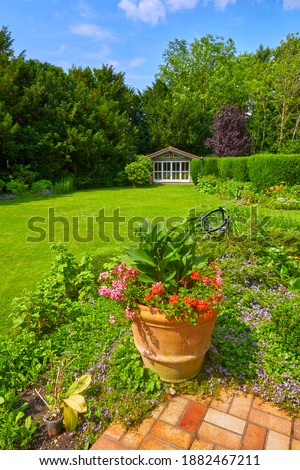 Well-kept garden with a colorful flower bed, garden shed and pond. Royalty-Free Stock Photo #1882467211