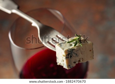 Blue cheese on a fork and red wine.