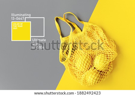 Yellow Cotton net bag with lemons on Grey background. Colors of the year 2021 Ultimate Grey and Illuminating. Color trend palette. Stylish background