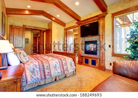 Beautiful gold bedroom with ceiling beams and fireplace.