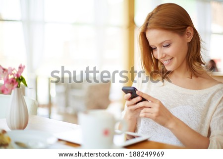 Image of young female reading sms on the phone in cafe Royalty-Free Stock Photo #188249969