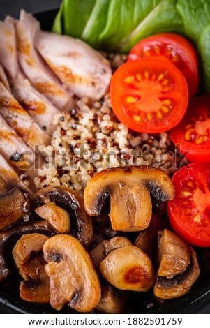 bowl of healthy quinoa with grilled chicken and vegetables on a dark rustic background