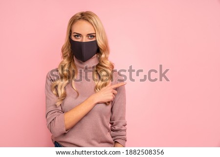 Young woman in pink blouse, sterile face mask to safe from coronavirus virus covid-19 during pandemic quarantine pointing fingers on workspace mock ups copy space isolated on pastel pink background