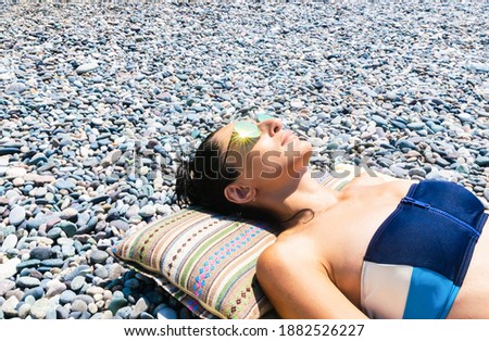 Young caucasian woman head lay on pillow with rocky beach beackground