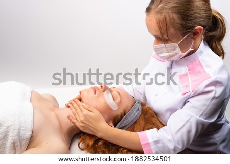 The beautician makes a facial massage for a young girl. Healthy skin concept. Photo on a white background.