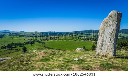 Hiking to the top of the Lizieux Peak (pic du Lizieux) with view of the rural landscape, and in the foreground a menhir