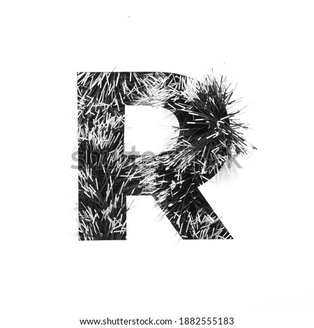 Black letter R of monochrome tinsel and paper cut isolated on white. English alphabet for minimalistic design