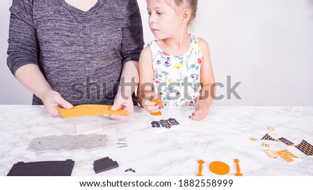 Little girl and her mother are working on a Halloween craft project.