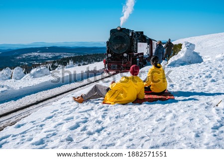 couple men and woman hiking in the Harz national park Germany, Steam train on the way to Brocken through the winter landscape, Famous steam train through the winter mountain. Brocken, Harz Germany Royalty-Free Stock Photo #1882571551