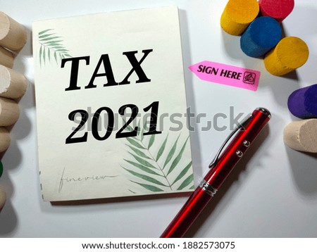 Selective focus.TAX 2021 in black word on notepad with pen and wooden blok on white background.Business finance concept idea.