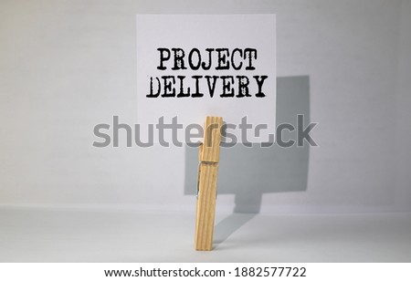 Notepad with text PROJECT DELIVERY on business charts and pen.
