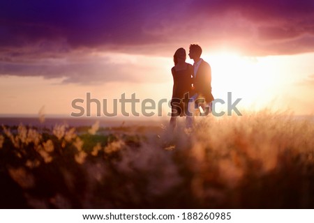 Young couple enjoying the sunset in the meadow