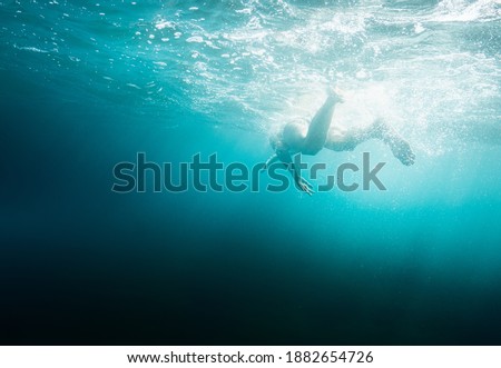 Person swimming into sea deep water from below