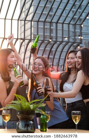 Group of young beautiful Asian girl gang best friends having party at rooftop clinking bottles together.Girls toasting bottles feeling happy enjoy, fun with smile face.