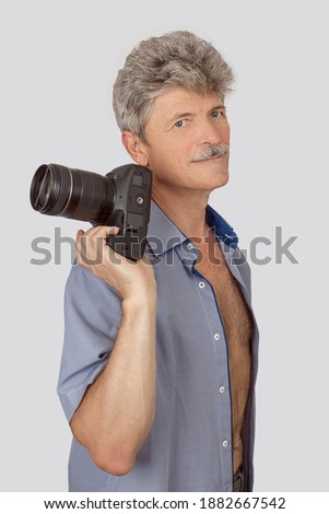 Portrait of handsome elderly man with camera isolated over grey background
