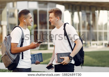 Students in a park. Boys in a university campus . Friends with a books.