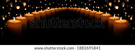 The flame of many white candles on a black background with a Golden bokeh. Banner with space for text.	