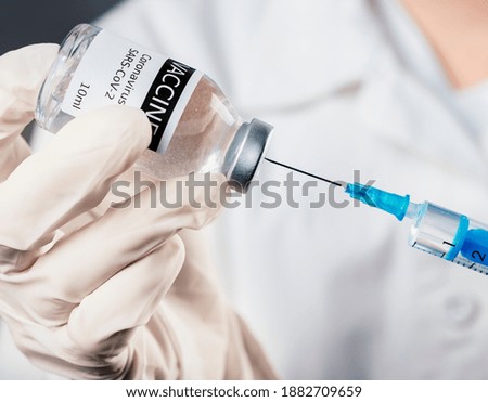 Doctor holding a syringe with a single bottle vial of Covid-19 vaccine for children or adults. Concept fight against virus. Close up detail. Medical concept vaccination hypodermic injection treatment.