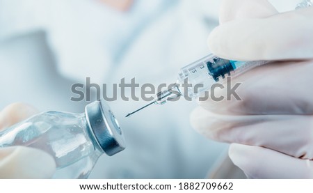 Doctor holding a syringe with a single bottle vial of Covid-19 vaccine for children or adults. Concept fight against virus. Close up detail. Medical concept vaccination hypodermic injection treatment. Royalty-Free Stock Photo #1882709662