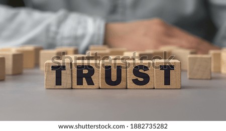 The word TRUST made from wooden cubes. Conceptual photo. Selective focus. Shallow depth of field on the cubes