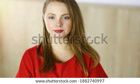 Head shot of a smart confident smiling millennial european woman standing with folded arms at home