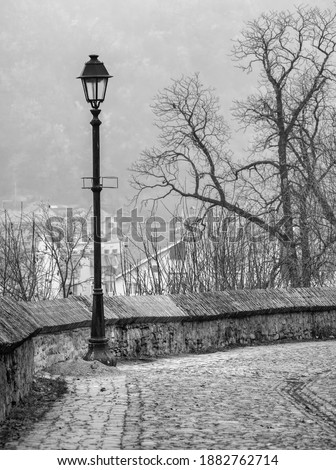 Old black and white picture of a street lamp and the cobblestone streets in the medieval citadel of Sighisoara