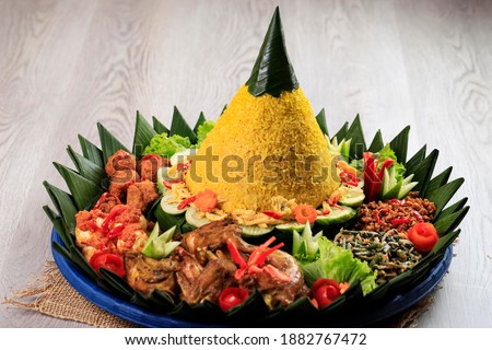 Yellow rice in a cone shape. In Indonesia called "Nasi Tumpeng" A festive Indonesian rice dish with side dishes Royalty-Free Stock Photo #1882767472