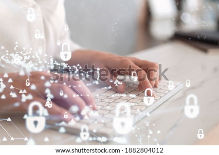 A woman programmer is typing a code on computer to protect a cyber security from hacker attacks and save clients confidential data. Padlock Hologram icons over the typing hands. Formal wear. Royalty-Free Stock Photo #1882804012