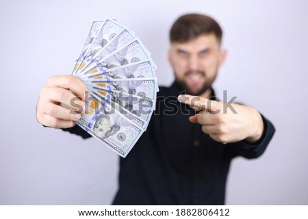 a male businessman holds bills in his hands and points at them with his index finger