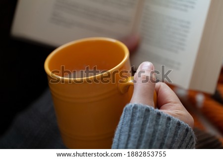 Woman holding book and coffee cup on blanket.Coffee and book concept.