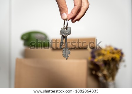 Photo of cardboard boxes, man's hand with key chain, open door in new apartment.
