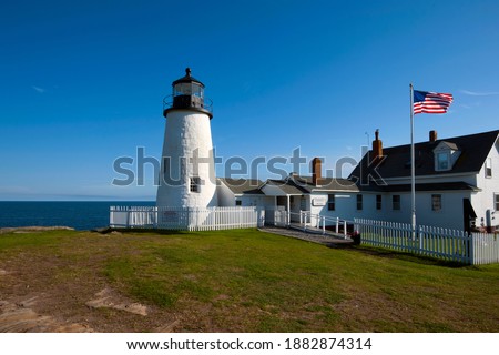 Pemaquid Point Lighthouse on a sunny summer day in Maine. American flag waves next to the beacon  