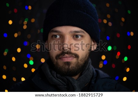 Young man closeup portrait in a studio shot with holiday lights in the background.