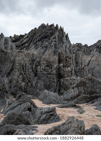 British Coastal Jagged Rock Formations with Sandy Beach Royalty-Free Stock Photo #1882926448