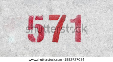 Red Number 571 on the white wall. Spray paint.