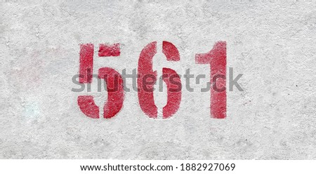 Red Number 561 on the white wall. Spray paint.