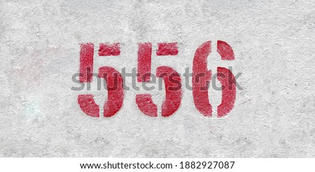 Red Number 556 on the white wall. Spray paint.