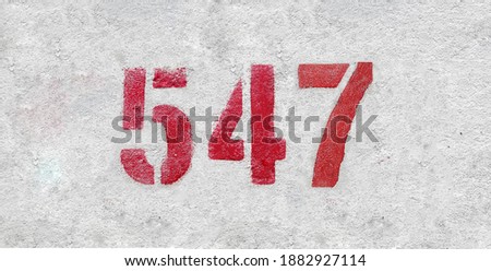 Red Number 547 on the white wall. Spray paint.