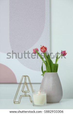 Vase with beautiful tulips, burning candle and decorative letter on table indoors, space for text. Interior elements