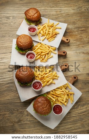 Set of burgers with french fries and ketchup sauce. Big hamburgers and french fries on wooden table background. Fast food set background. Restaurant burger menu 