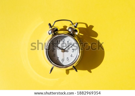 gray alarm clock on illuminating background, top view