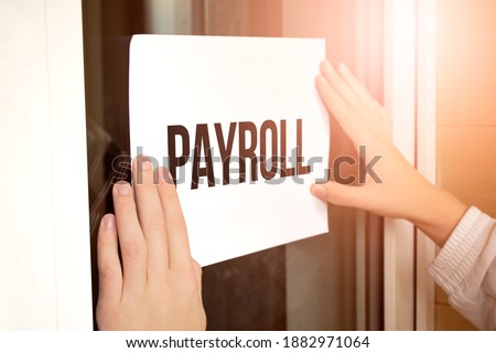 Closeup of owner holding text Payroll in store