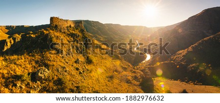 Wide angle Dramatic panorama of sunset over the valley next to Tmogvi fortress with beautiful golden autumn nature in background.Travel in Georgia.