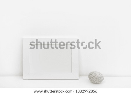 White frame on the table and round stone. Minimalism in design.