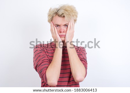 Young handsome Caucasian blond man standing against white background Tired hands covering face, depression and sadness, upset and irritated for problem