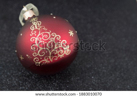 One red Christmas ball with a picture of a Christmas tree on a black background. Place for text